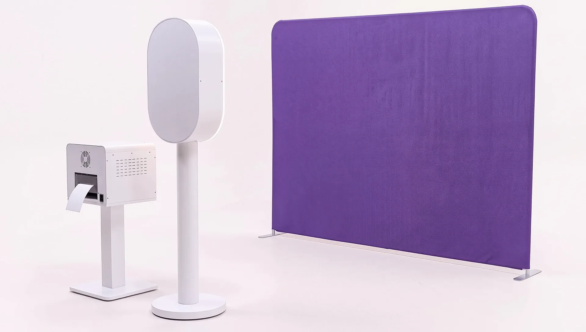 A Kaluara photobooth on its stand with a ring light around the screen, a printer beside it and a violet backdrop behind.